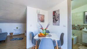 A dining area with a table, chairs, a vase with flowers, and a basket of fruit. - Apartment 'Sud In Villa Sele' with Sea View, Wi-Fi and Air Conditioning (Fontane Bianche)