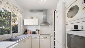 Una cocina moderna con armarios blancos, horno integrado y ventana con vistas a zonas verdes.