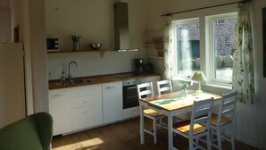Eine kleine Küche mit weißen Schränken, einer Holzarbeitsplatte, einem eingebauten Backofen und einem Fenster mit Vorhängen.