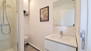 A bathroom with a shower, toilet, sink, and a framed picture on the wall.