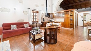 Un amplio salón con un sofá rojo, muebles de madera, una cocina con armarios de madera y una pared de piedra.