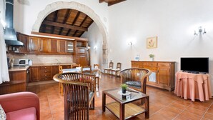Amplia sala de estar con cocina, mesa de comedor, sillas, sofá y televisor.