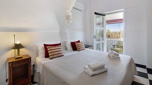 Ein Hotelzimmer mit Bett, Nachttischlampe, Klimaanlage und Blick ins Freie.