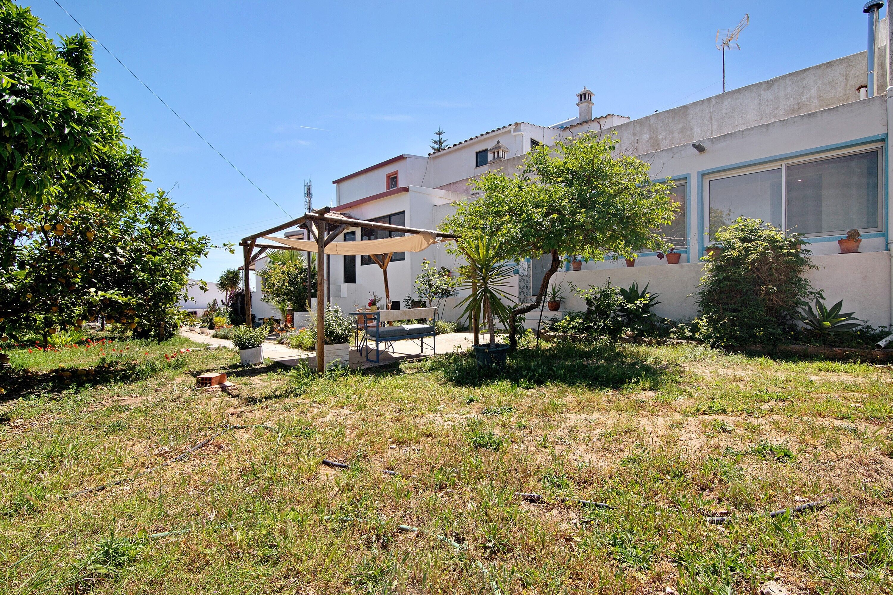 A residential area with a house, a covered patio, and a garden with various plants.