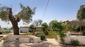A patio area with a pergola, outdoor seating, and a pool in the background.