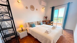 Ein Schlafzimmer mit Bett, Nachttisch, Lampe, Wanddekorationen und einem Fenster mit Vorhängen.