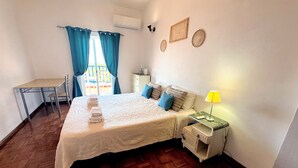 Ein Schlafzimmer mit Bett, Nachttisch, Lampe und Schreibtisch mit Stuhl.
