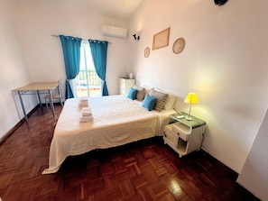 Une chambre à coucher comprenant un lit, une table de chevet, une lampe et un bureau avec une chaise.