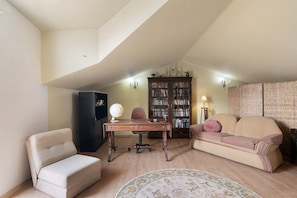 Um quarto com uma escrivaninha, uma cadeira, um sofá, uma estante e um abajur.