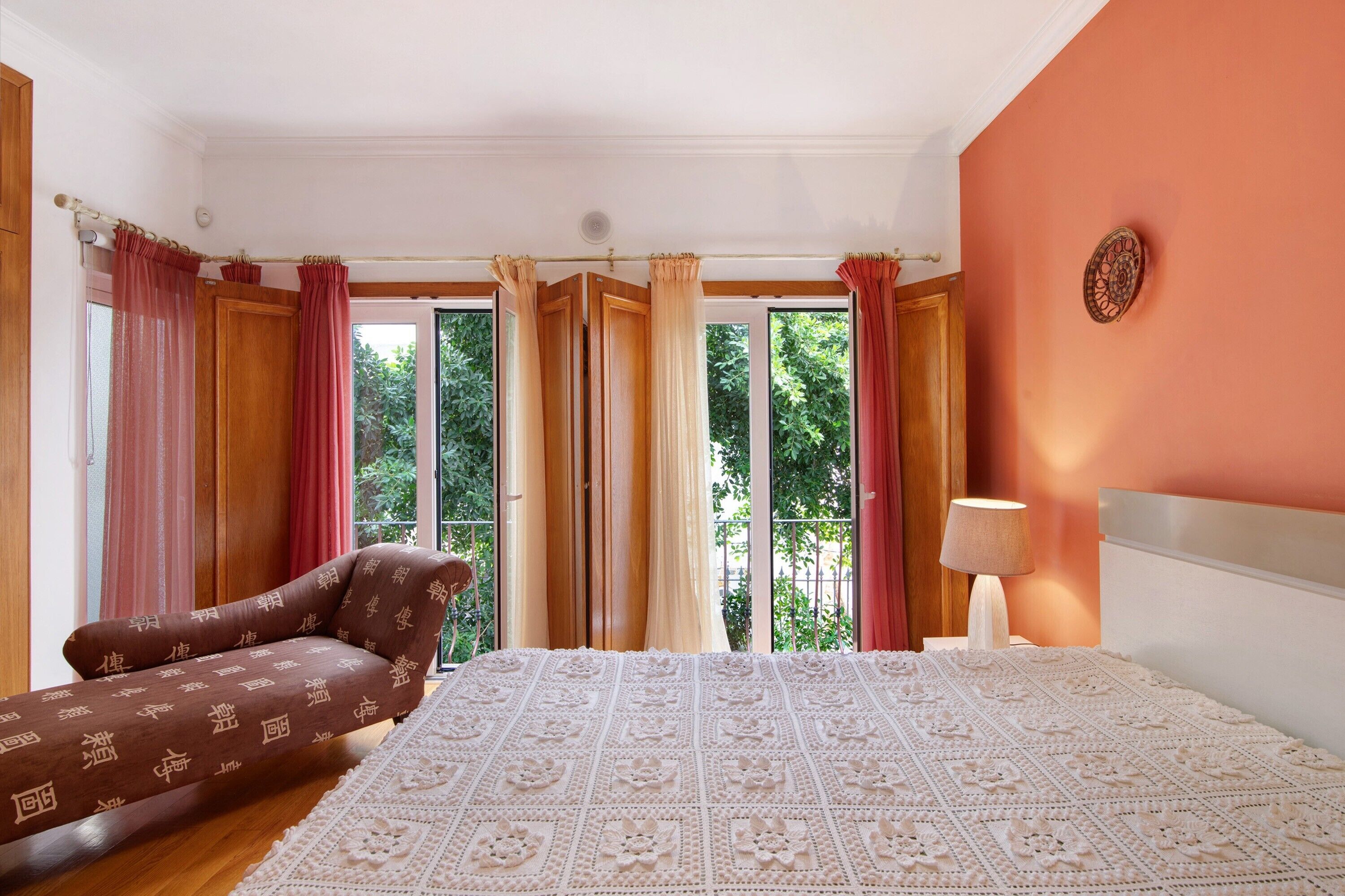 Ein Schlafzimmer mit einem Bett, einem Schlafsofa, einem Fenster mit Vorhängen und einer Wanddekoration.