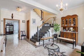 Um hall espaçoso com uma escadaria imponente, um armário de madeira e um candelabro.