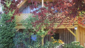 A rustic wooden building with a yellow roof, surrounded by dense foliage and flowering plants. - Vacation apartment 03 for friends (Zinnowitz)