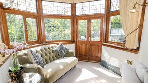 A corner room with a cushioned bench, a small table, and a potted plant. - Gwern Borter Manor (Conwy)