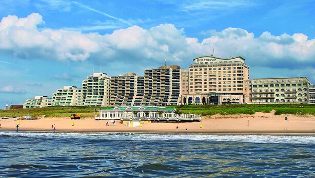 Een strandhotel met meerdere hoge gebouwen, een strand en uitzicht op de oceaan.