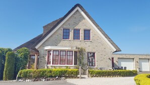 Een stenen huis met een puntgevel, erker en garage.