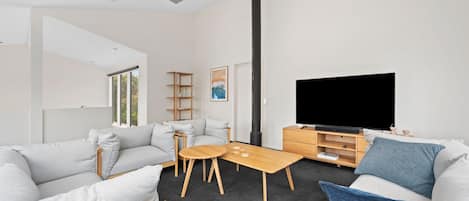 A modern living room with a sofa, coffee table, TV, and a fireplace.