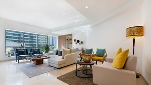 Una sala de estar moderna con un sofá, sillones, una mesa de centro y un ventanal con vistas a la ciudad.