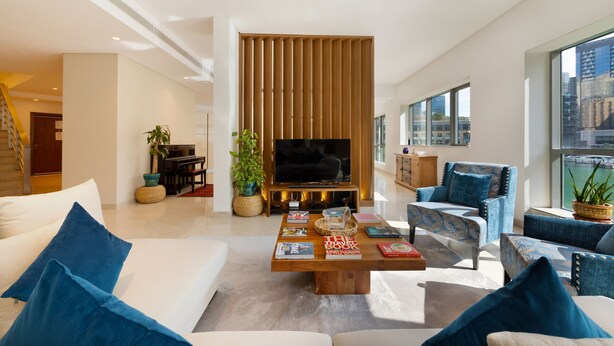 Una sala de estar moderna con un televisor de pantalla plana, un mueble de madera para entretenimiento y un amplio ventanal con vista a la ciudad.