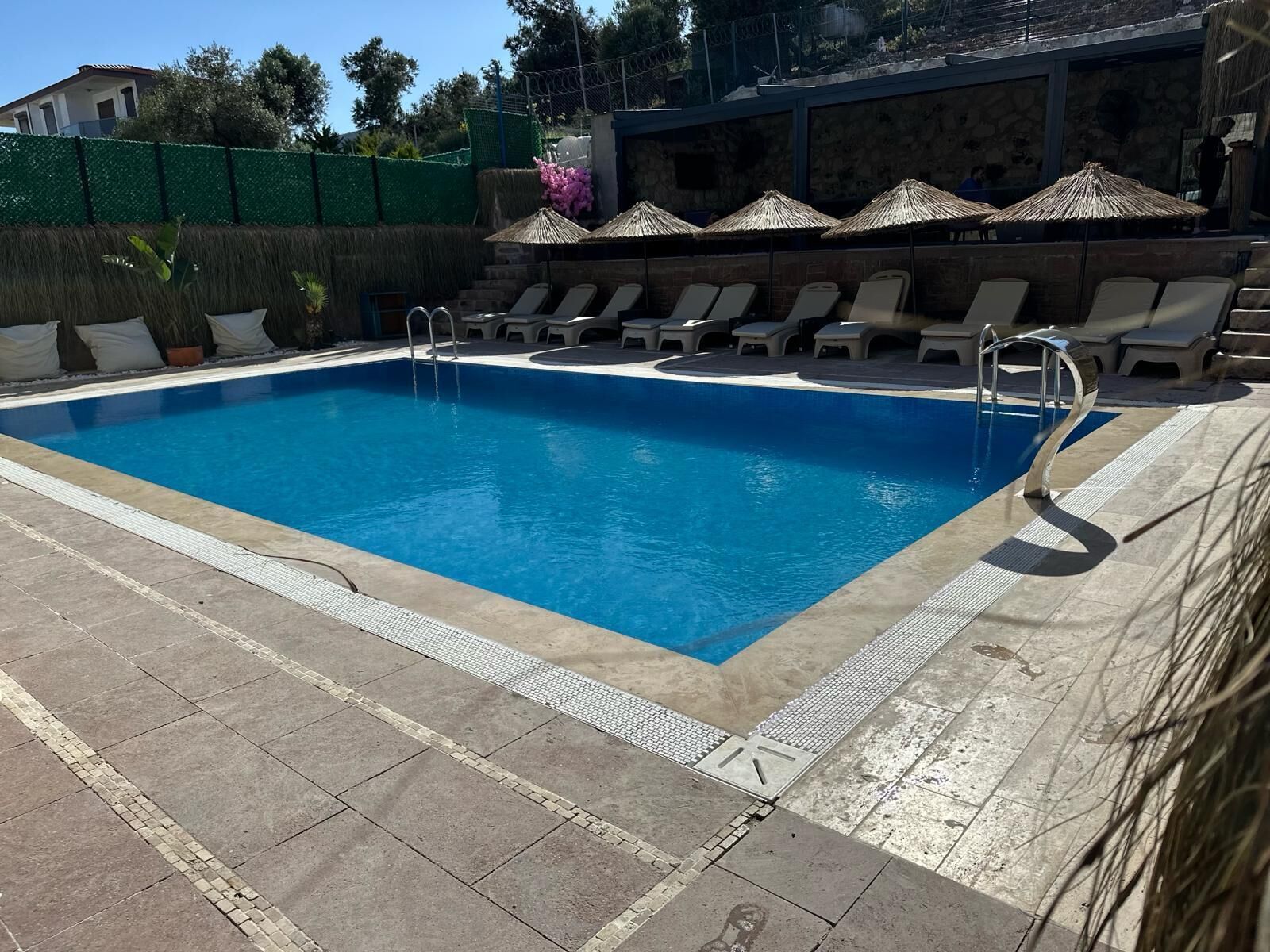 Una piscina con sillas de descanso y una pared de piedra al fondo.