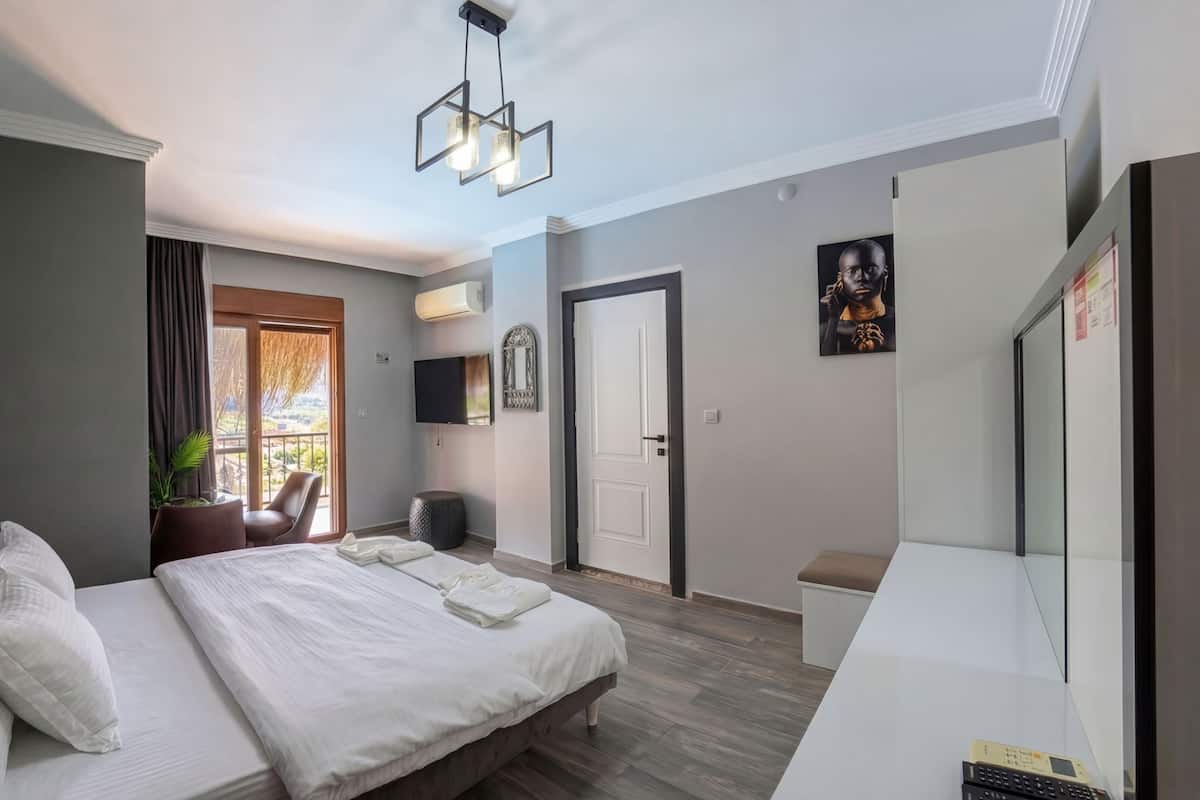 A hotel room with a bed, a chair, a TV, and a door.