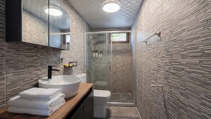 A modern bathroom with a large sink, toilet, and glass shower enclosure. - Stone House Foca Butik Otel (Foça)