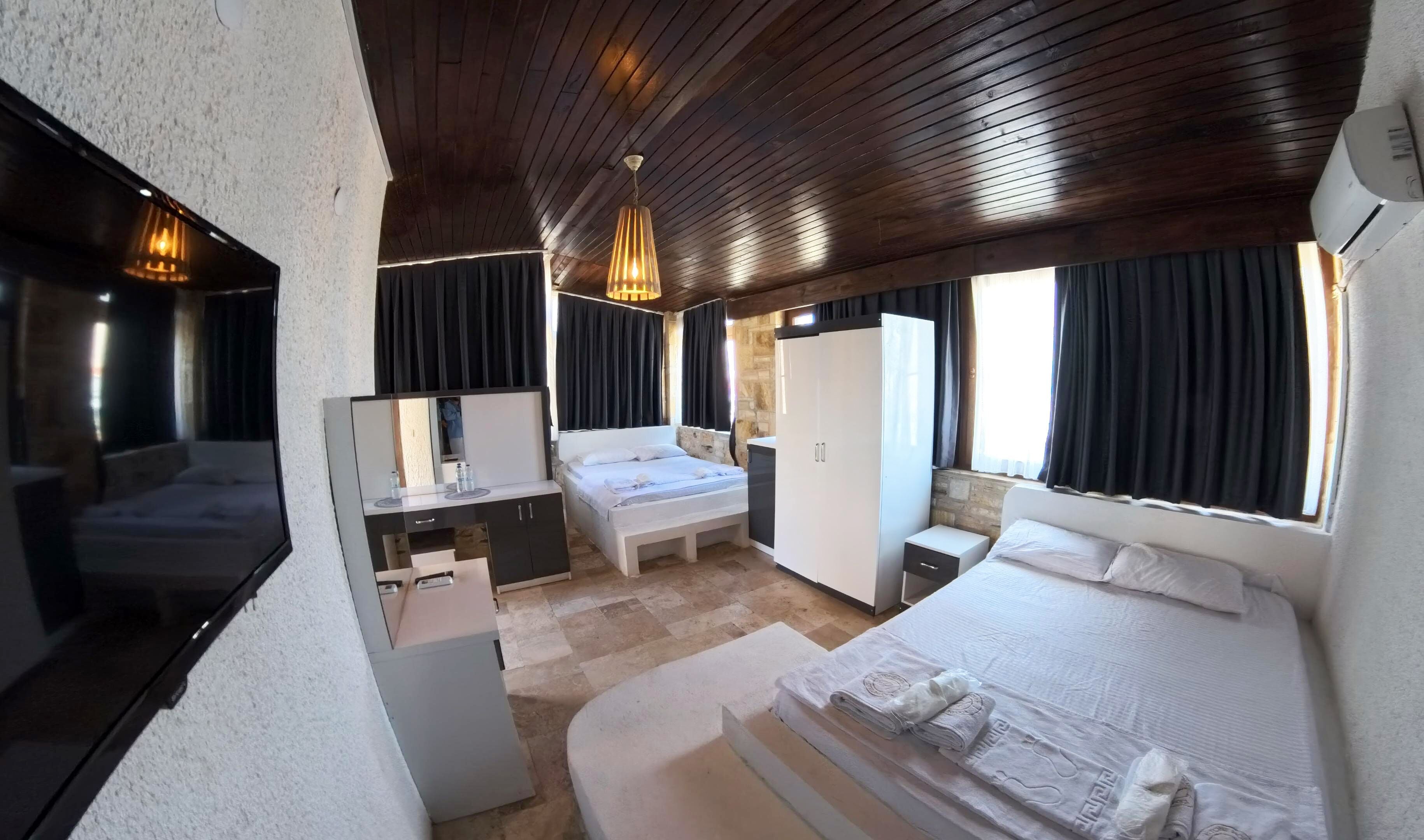 A hotel room with a bed, a desk, a mirror, a wardrobe, and a window with curtains.