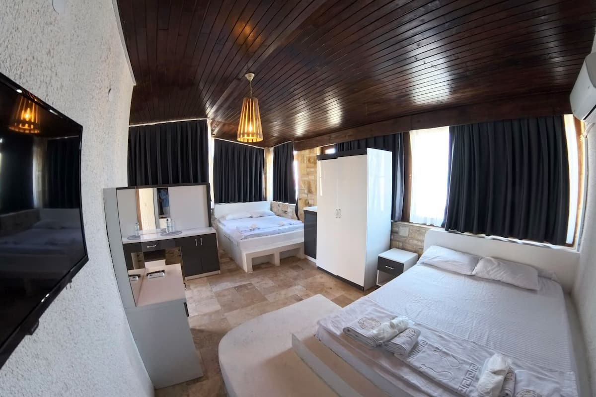 A hotel room with a bed, a desk, a mirror, a wardrobe, and a window with curtains.