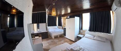A hotel room with a bed, a desk, a mirror, a wardrobe, and a window with curtains.