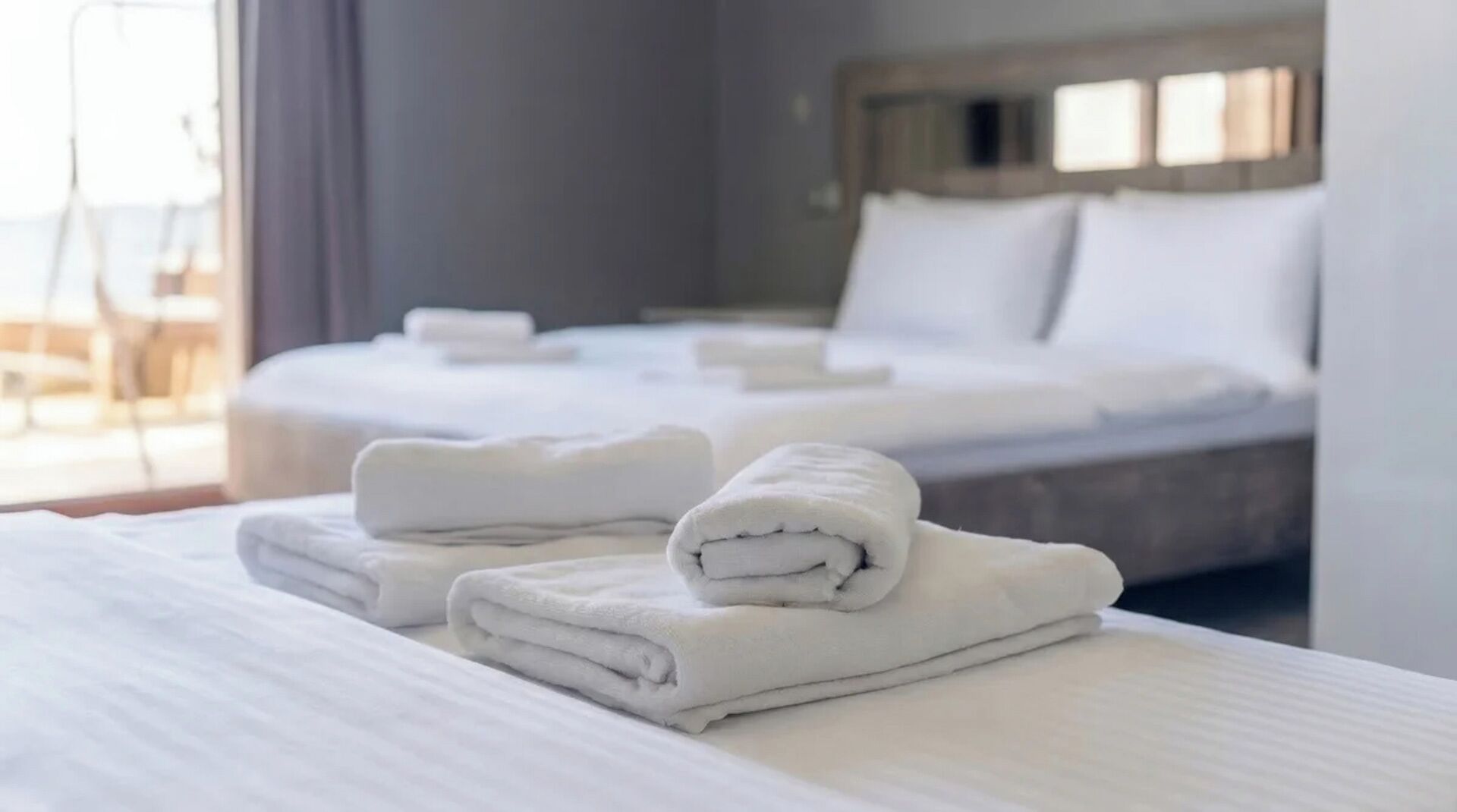 A hotel room with two beds, neatly made with white linens and towels.