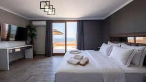A hotel room with a bed, a TV, a desk, and a view of the sea. - Stone House Foca Butik Otel (Foça)
