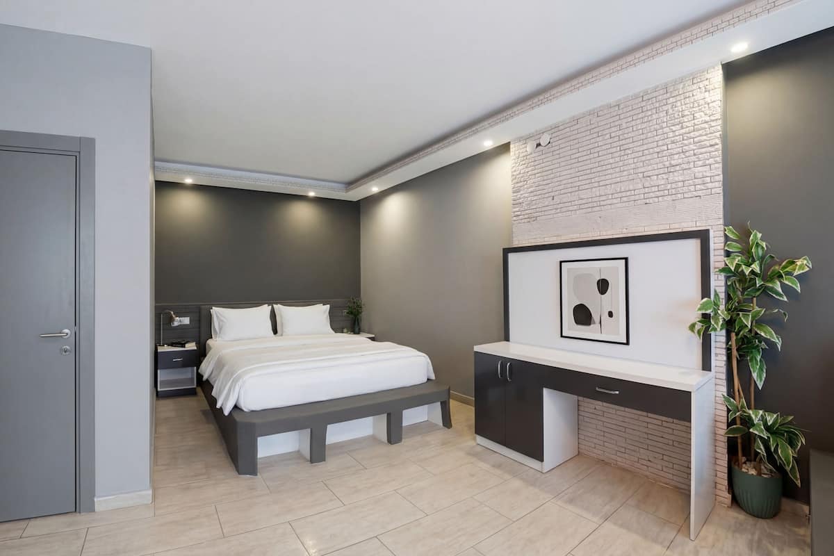 A modern bedroom with a bed, bedside table, and a built-in desk with a mirror.
