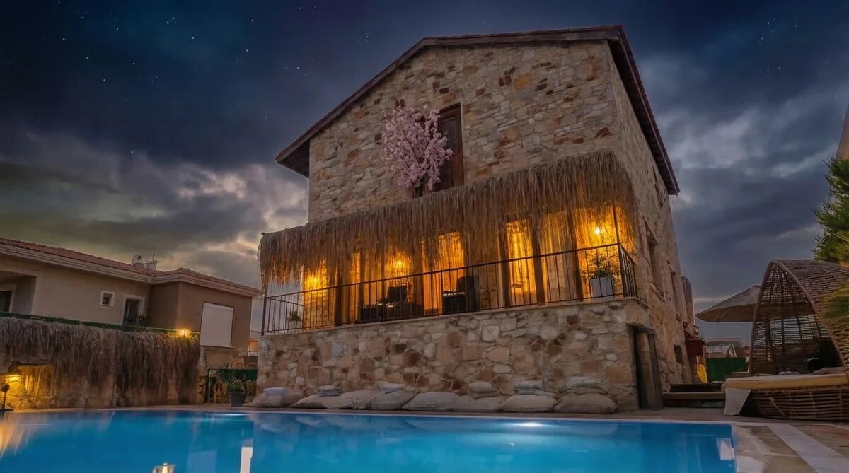 Un edificio de piedra con piscina, que cuenta con un balcón con barandilla y vistas al cielo nocturno.