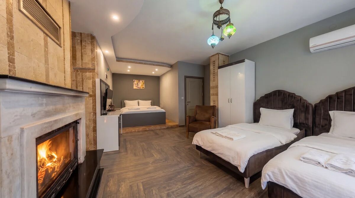 Une chambre d’hôtel avec une cheminée, deux lits, un coin salon et une grande armoire.