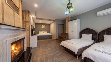 Une chambre d’hôtel avec une cheminée, deux lits, un coin salon et une grande armoire.