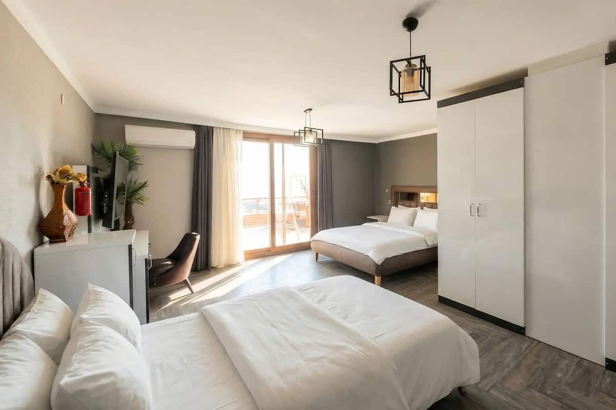 A hotel room with a bed, a desk, a chair, a wardrobe, and a sliding door to a balcony.