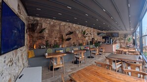 A restaurant with stone walls, wooden tables, and a large window. - Stone House Foca Butik Otel (Foça)