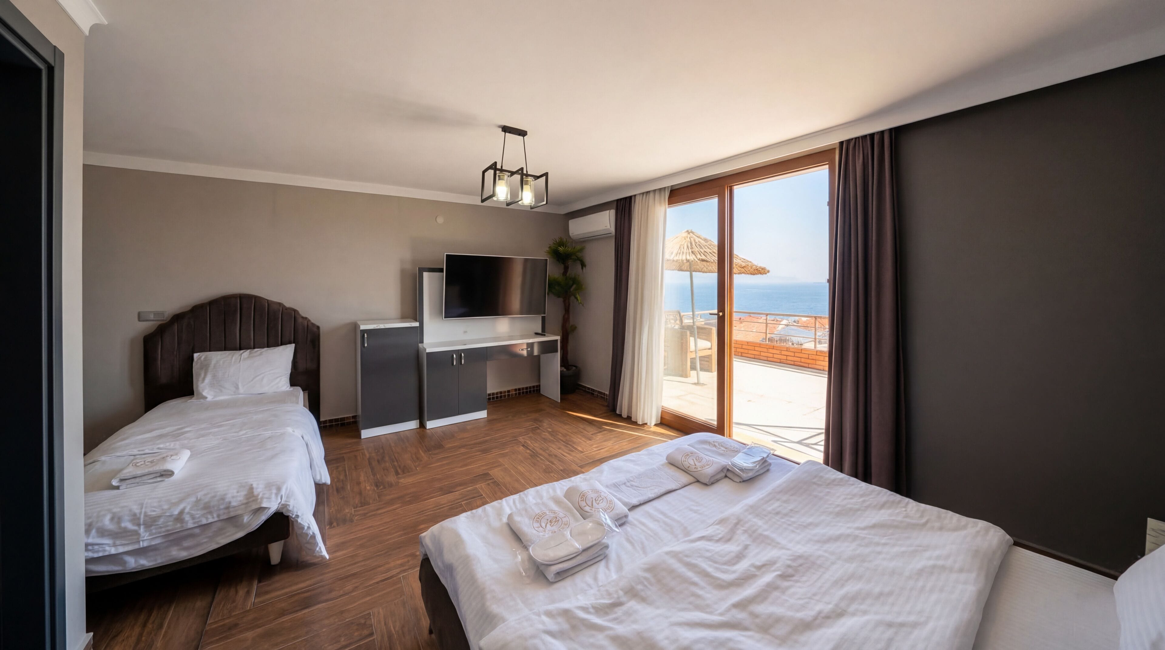 Et hotelværelse med to senge, et fjernsyn, et skrivebord og en balkon med havudsigt.