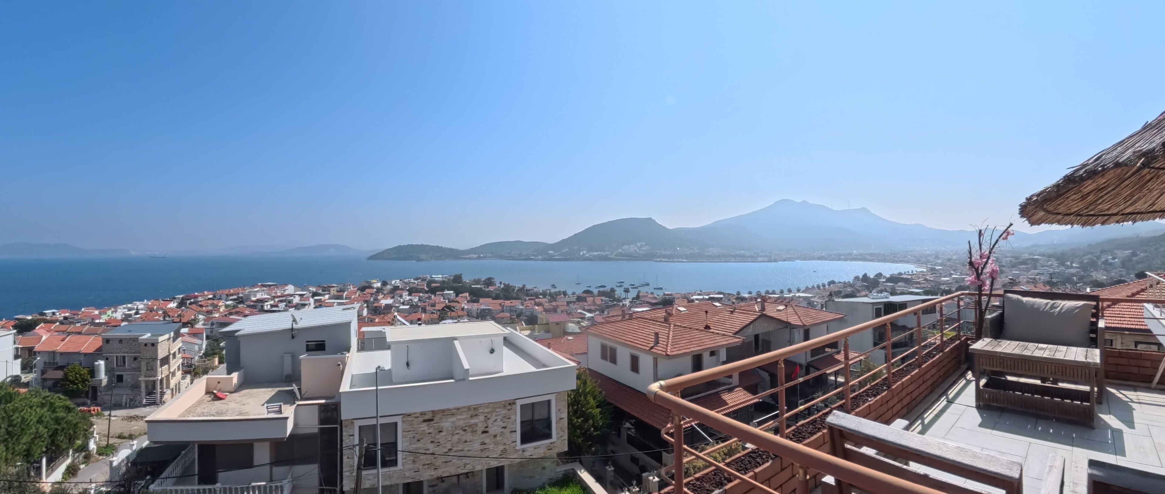 A coastal town with buildings, a mountain, and a clear sky.