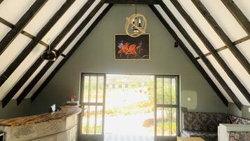 An attic room with a high ceiling, a chandelier, a framed floral artwork, a reception desk, and a view of the outdoors.