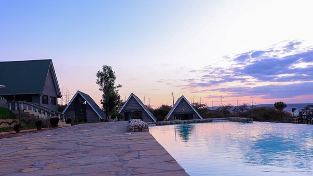 A pool area with a stone pathway leading to a building with a green roof and a modern design. - Outback Kenya Lodge (Machakos)