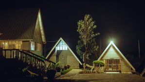 A row of triangular-roofed buildings at night, illuminated by street lighting. - Outback Kenya Lodge (Machakos)