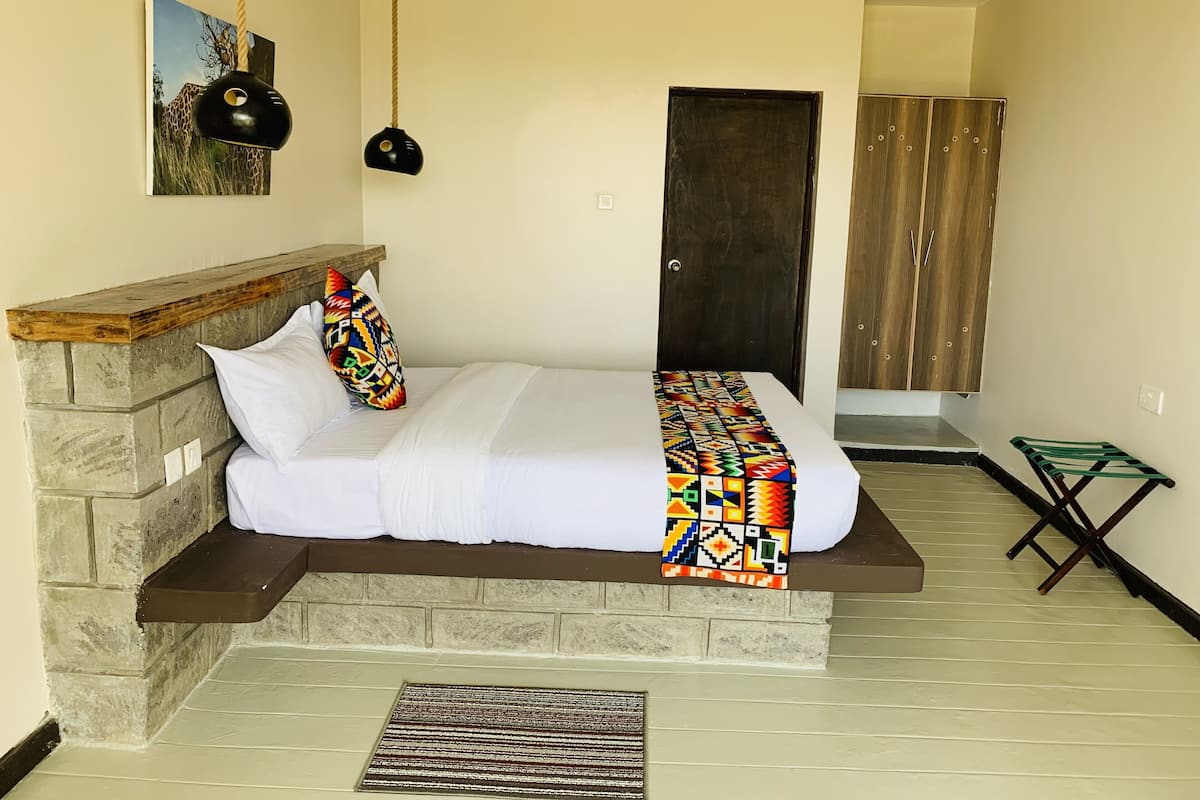 A bed with a stone headboard, a colorful blanket, and a hanging light fixture.