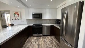 Eine moderne Küche mit einem Edelstahlkühlschrank, einer Mikrowelle und einem eingebauten Backofen.
