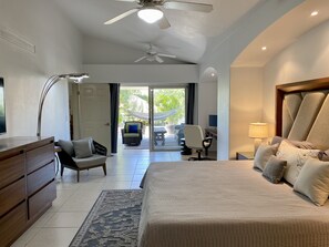 A modern bedroom with a large bed, a desk, a chair, and a ceiling fan.