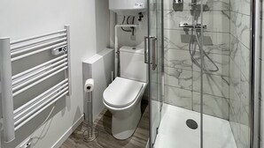 A modern bathroom with a glass-enclosed shower, a toilet, and a wall-mounted radiator. - 🌿 L'Oliveraie 🌿 (Brioude)