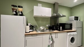A modern kitchen with white appliances, a stainless steel range hood, and a built-in washing machine. - 🌿 L'Oliveraie 🌿 (Brioude)