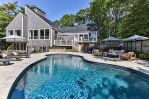 A two-story house with a swimming pool, outdoor furniture, and a covered patio area.