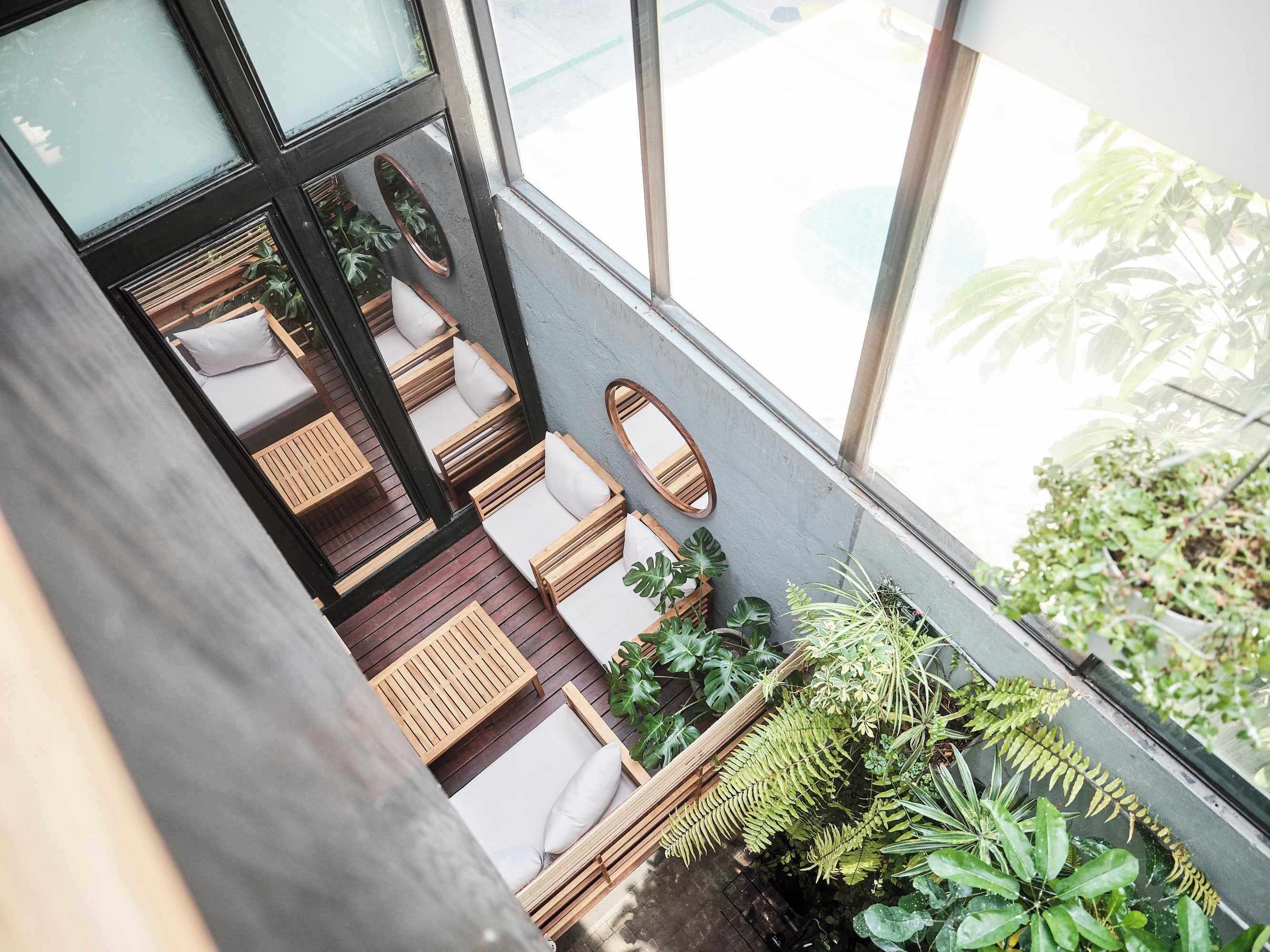 Een modern interieur met een hoge plafonds, houten meubels en grote ramen met uitzicht op een tuin.