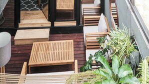 Ein modernes Interieur mit einer Holzbank, einer Hängematte und topfständigen Pflanzen.