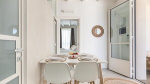 A dining area with a table set for two, a mirror on the wall, and a sliding glass door leading to a balcony. - 2940 Palma Residence- Appartamento Notos by Barbarhouse (Melendugno)
